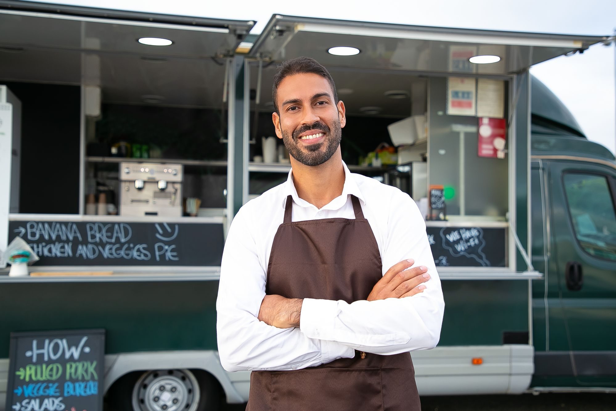 Uśmiechnięty właściciel food trucka z założonymi rękami